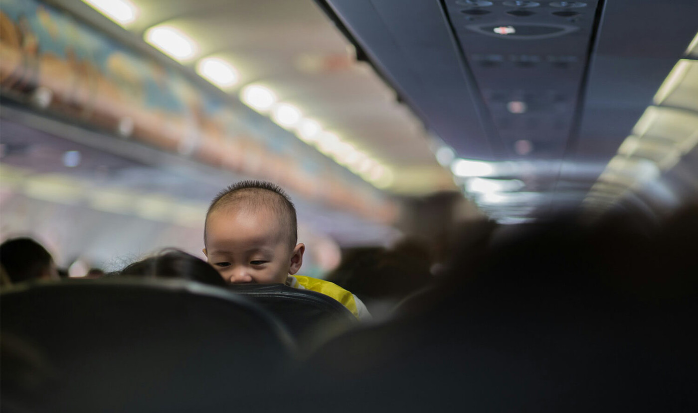 Un bambino molto piccolo in viaggio in aereo, tenuto in braccio