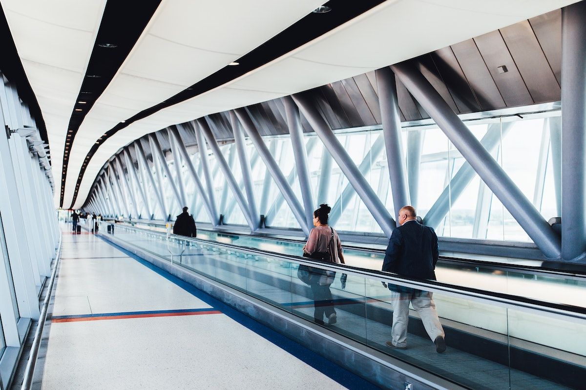 Travelers walk on a moving walkway between airport terminals