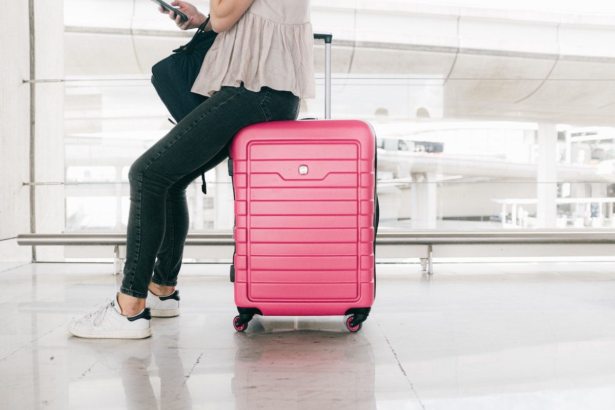 Woman sits on her luggage while waiting for her flight to depart