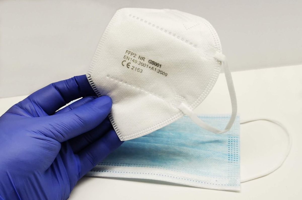 Person wearing nitrile gloves compares an FFP2 mask with a surgical mask.