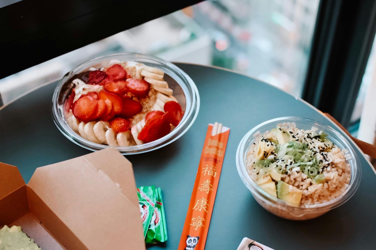Packed lunch of salad, and fruit with chopsticks.