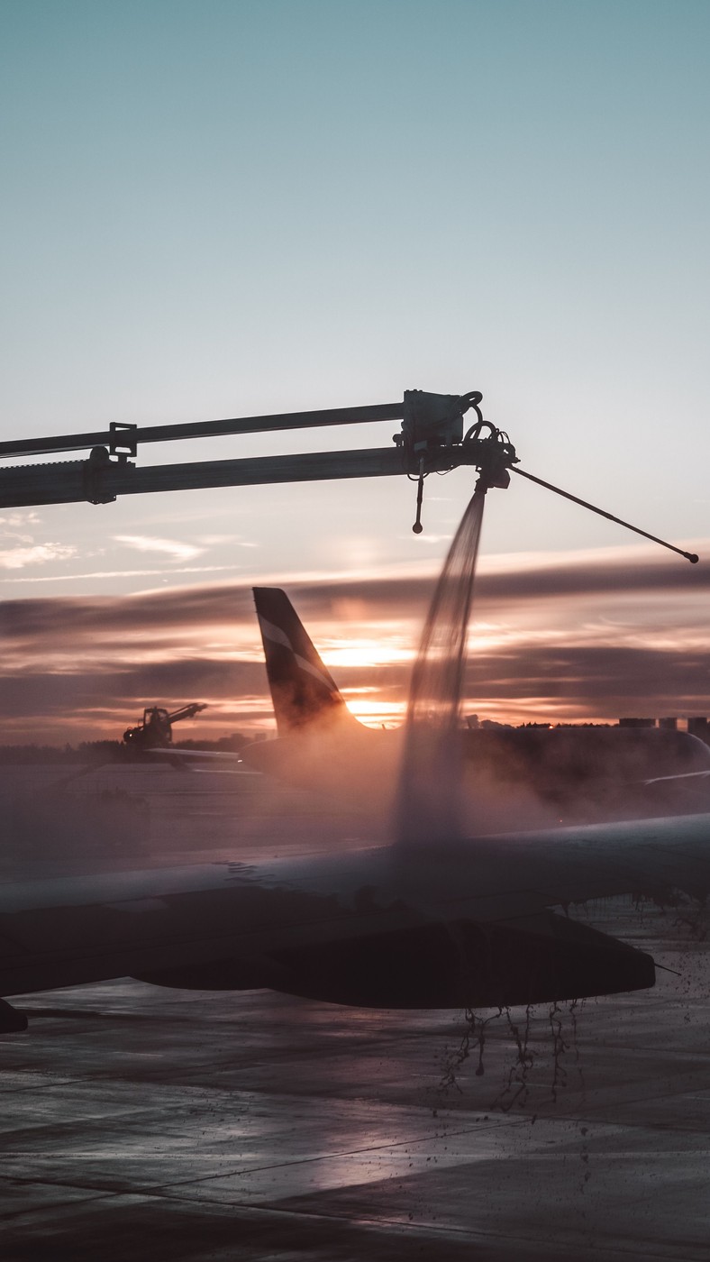 Aircraft being sprayed with de-icing fluid on a snowy airport apron