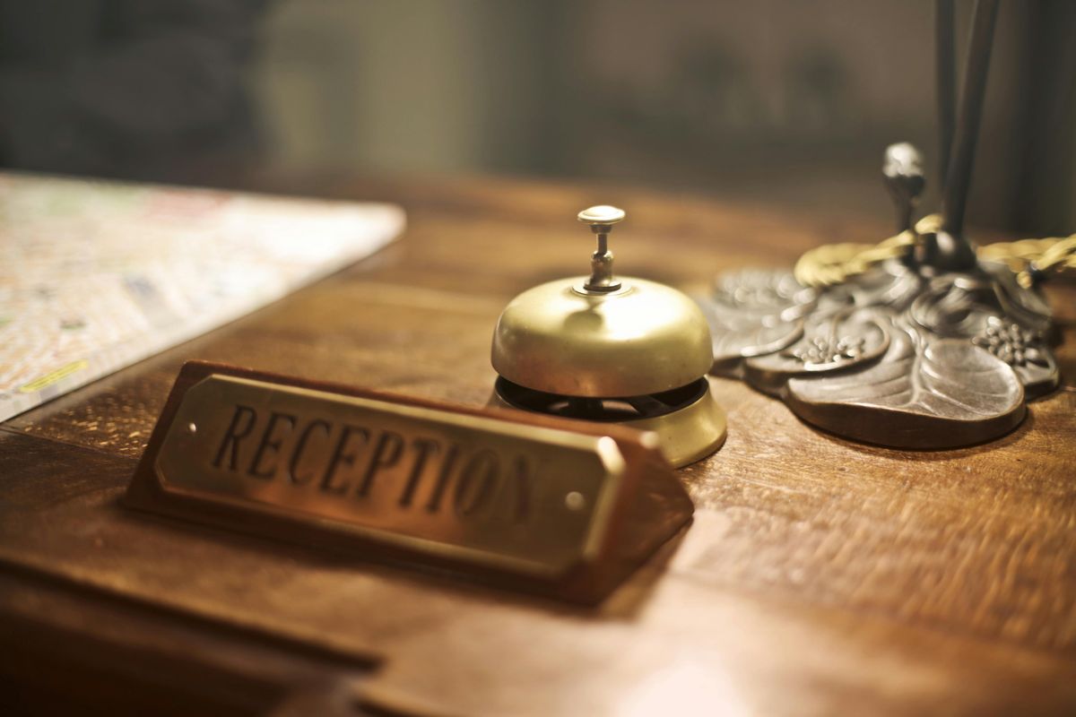 Reception desk at the hotel displaying a bell, notepad, brass pen holder, and an antique plaque saying "reception".