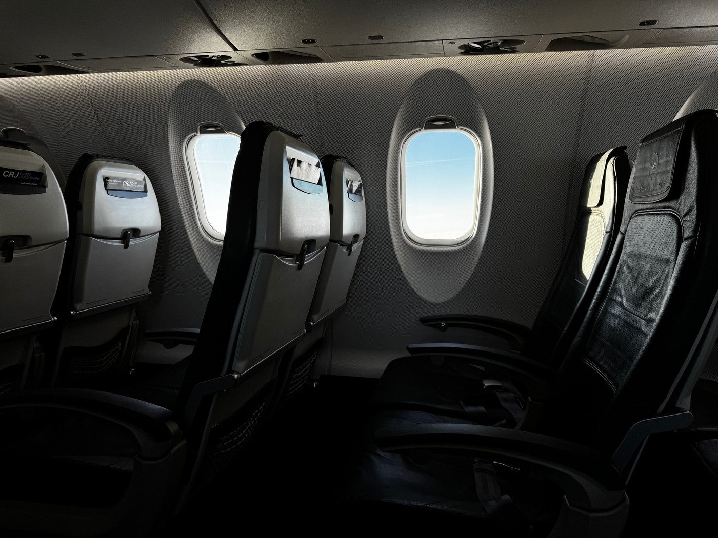 Two airplane seats next to each other by a window
