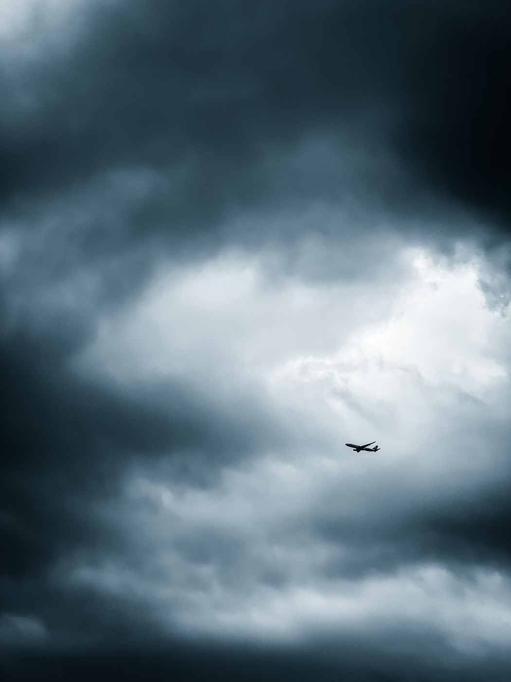 Airport departures board showing a delayed flight while the sky outside is clear