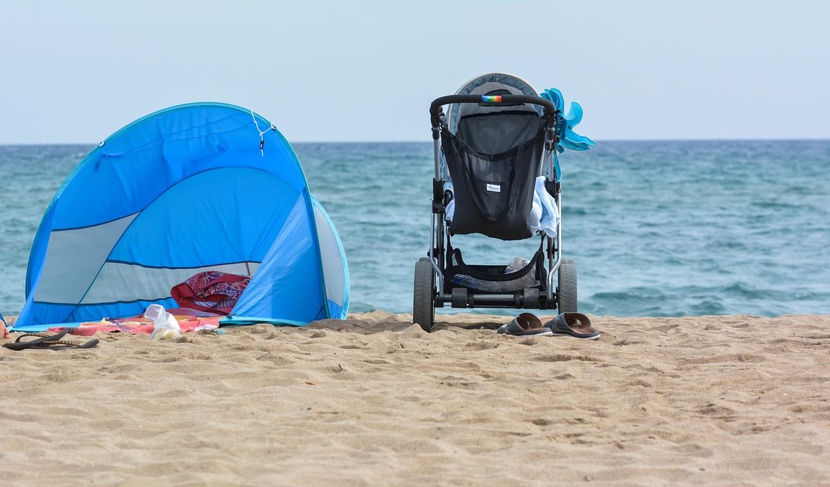 Baby stroller by the beach with a tent beside it.