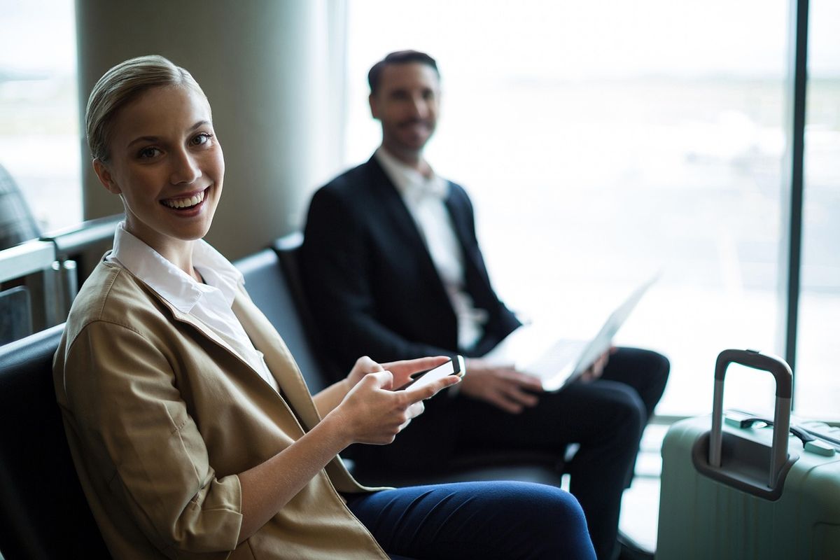 Woman and man sitting at terminal looking at phone booking