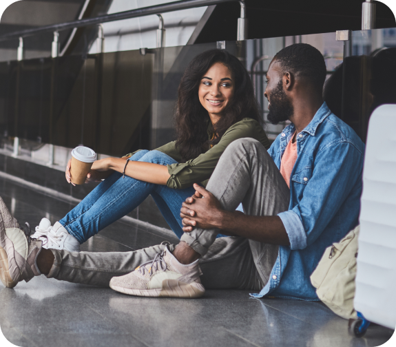 Two friends sitting at an airport and talking.